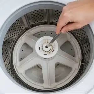 A hand using a silver tool to clean a dirty agitator